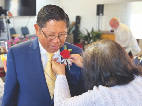 Pastor Ricardo Biscaro has a corsage pinned to his suit prior to the beginning of the inauguration ceremony. 