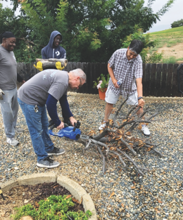 <p>MOVE members help clean up a yard in the community.</p><p>Los miembros de MOVE ayudan a limpiar un patio en la comunidad.</p>